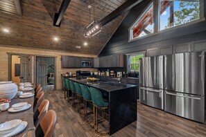 A modern kitchen with a central island, bar stools, stainless steel appliances, and a wooden ceiling. - Midnight in the Smokies, Sleeps 32, Pool, Hot Tub, Game Room with Arcade (Sevierville)