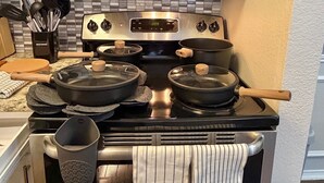 Une cuisine dotée d’une cuisinière en acier inoxydable, d’un four à micro-ondes placé au-dessus et d’un pare-feu carrelé.