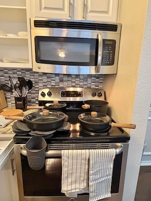 Una cocina con estufa de acero inoxidable, un microondas arriba y un salpicadero de azulejos.