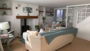 Una sala de estar acogedora con un sofá, una mesa con una lámpara, una chimenea y una escalera.