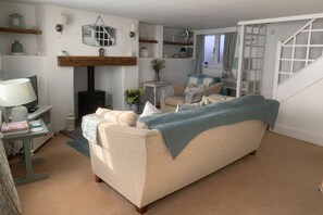 Ein gemütliches Wohnzimmer mit einer Couch, einem Tisch mit Lampe, einem Kamin und einer Treppe.