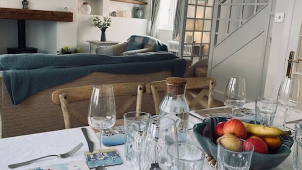Un área de comedor con una mesa dispuesta para dos personas, un frutero y una botella de agua.
