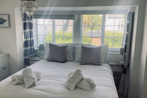 Ein Hotelzimmer mit einem großen Bett, zwei Nachttischen, einer Stehlampe, einer Deckenleuchte und einem Fenster mit Vorhängen.