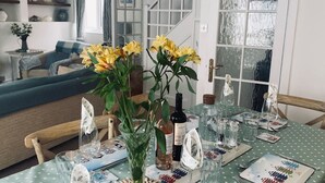 Un comedor con una mesa lista para dos personas, un sofá al fondo y una escalera que sube a otro nivel.