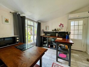 A compact kitchen with a microwave, a wooden table, and a window with curtains.