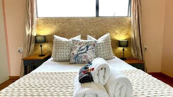 A hotel room with a bed, pillows, a lamp, and a towel arrangement.