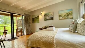 A bedroom with a bed, a large window, and a view of the outdoors. - Equleni Farm (Knysna)