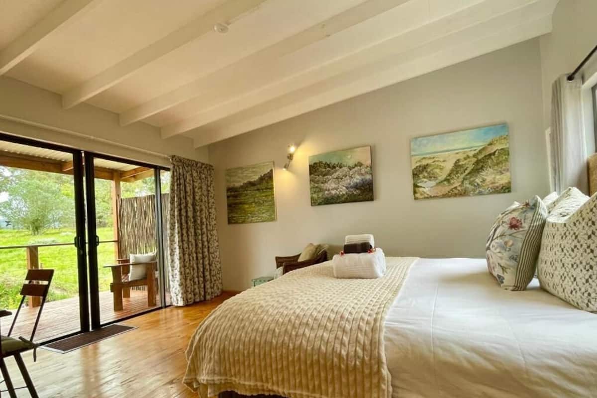 A bedroom with a bed, a large window, and a view of the outdoors.