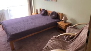 A single bed with a wooden frame, two bedside tables with lamps, a headboard, a window with curtains, and a painting on the wall. - Serce Gdyni by Grand Apartments (Gdynia)