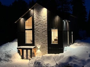 Een modern huis met een stenen gevel, grote ramen en een buitenkant bedekt met sneeuw.