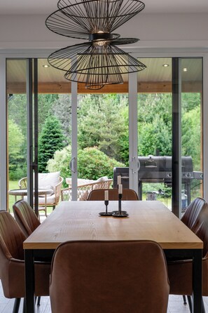 Een eethoek met een houten tafel, bruine stoelen en een moderne hanglamp.