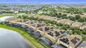 A residential area with modern houses, a lake, and solar panels on rooftops. - Luxury 8BR Lake View Villa Near Disney with Pool (Kissimmee)