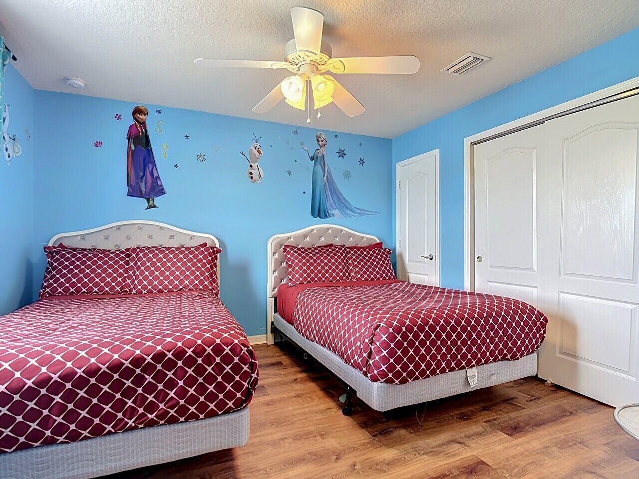 Een slaapkamer met twee bedden, een plafondventilator en een deur.