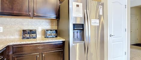 A kitchen with dark wooden cabinets, a stainless steel refrigerator, and a microwave.