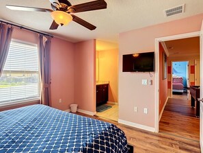 Ein Schlafzimmer mit Bett, Deckenventilator, Fernseher und Blick nach draußen.