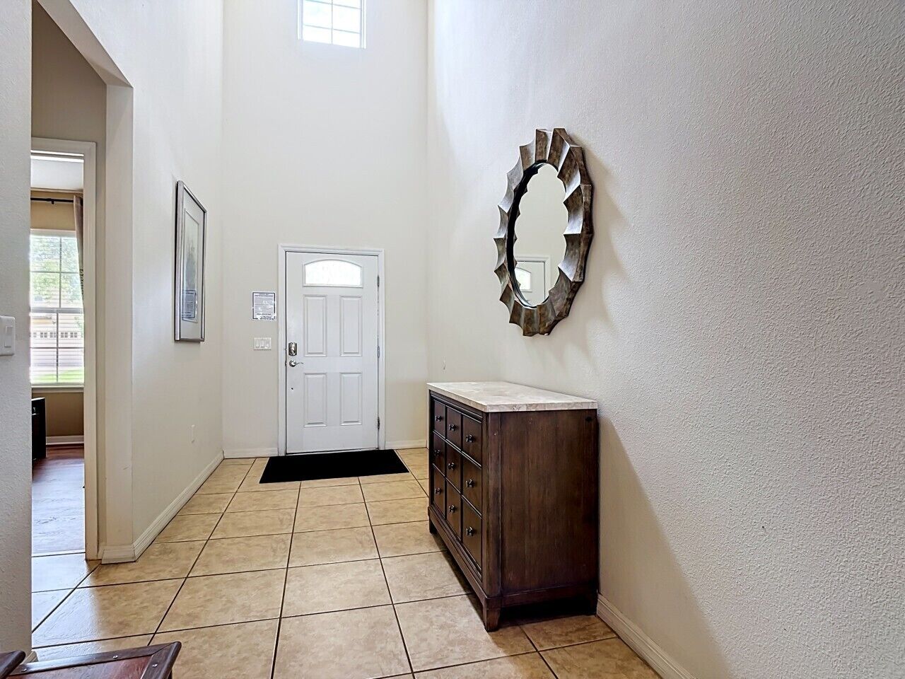 Un pasillo con una puerta, un armario de madera y un espejo decorativo en la pared.