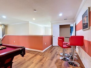 A pool table in a room with wooden flooring and red chairs. - 8BR Villa with Pool & Spa, Near Disney (Kissimmee)