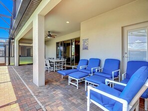 Ein überdachter Außenbereich mit blauen Loungesesseln und einem Tisch.