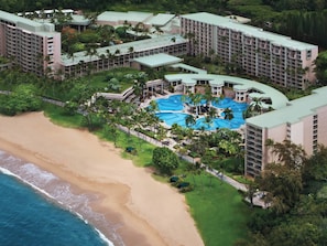 Ein Resort mit mehreren Gebäuden, einem zentralen Poolbereich und einem Strand.
