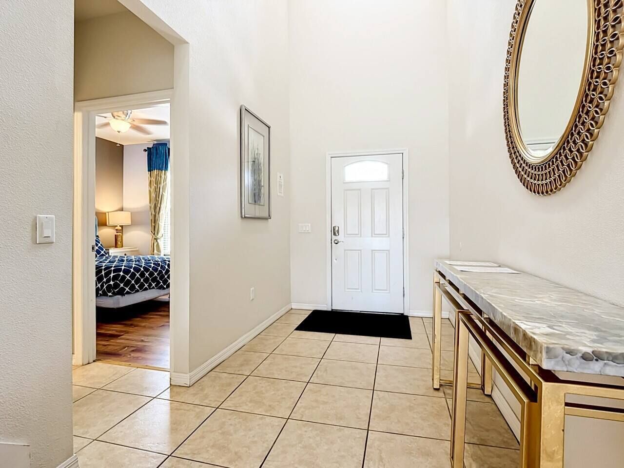 A hallway with a door, a framed picture, and a marble-topped table.
