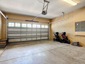 Un garatge amb una porta metàl·lica gran, un projector fixat al sostre i un cotxet de nens.