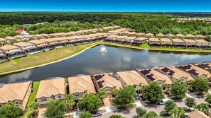 Ein Wohngebiet mit Häusern, die um einen zentralen Teich angeordnet sind, mit einem einheitlichen architektonischen Stil, gekennzeichnet durch flache Dächer und freiem Blick auf die umliegende Natur.