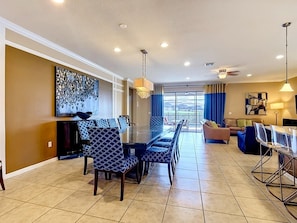 A spacious living area with a dining table, chairs, and a sofa. - Windsor at Westside 8BR + Water Slide, Near Disney (Kissimmee)