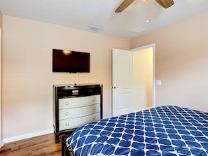 A bedroom with a bed, dresser, television, and a door. - Windsor at Westside 8BR + Water Slide, Near Disney (Kissimmee)