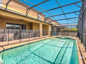 Una piscina amb zona coberta, gandules i vistes a un edifici amb balcó.