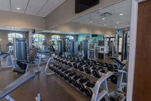 Un gimnàs amb diverses màquines i equipament per fer exercici, incloent pesos i aparells de musculació.