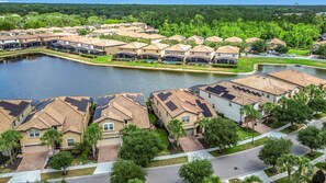 A residential area with houses, a lake, and solar panels on rooftops. - Windsor Westside 8BR Lake View Home Near Disney (Kissimmee)