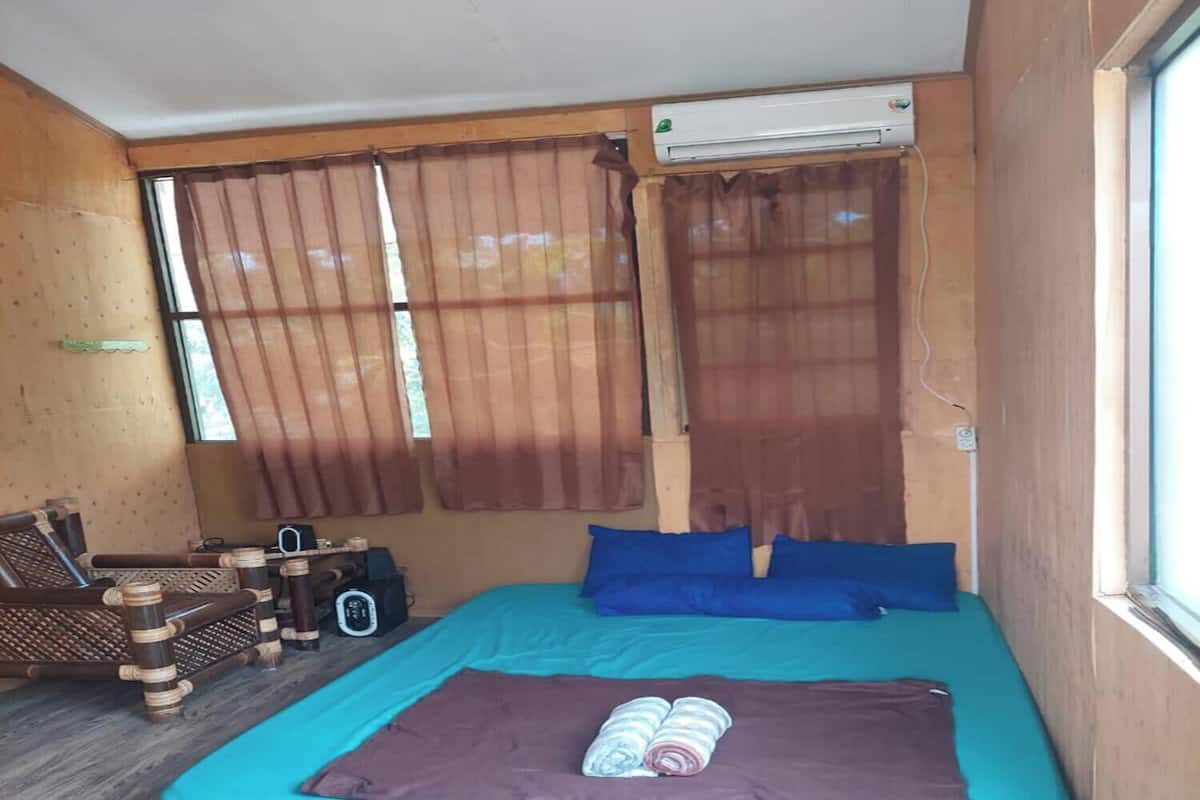 A room with a bed, a window with curtains, an air conditioning unit, and a wooden wall.