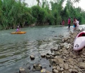 A river with a kayak, rocks, and people standing by the shore. - Cozzy Villa Delta Island (sumedang)
