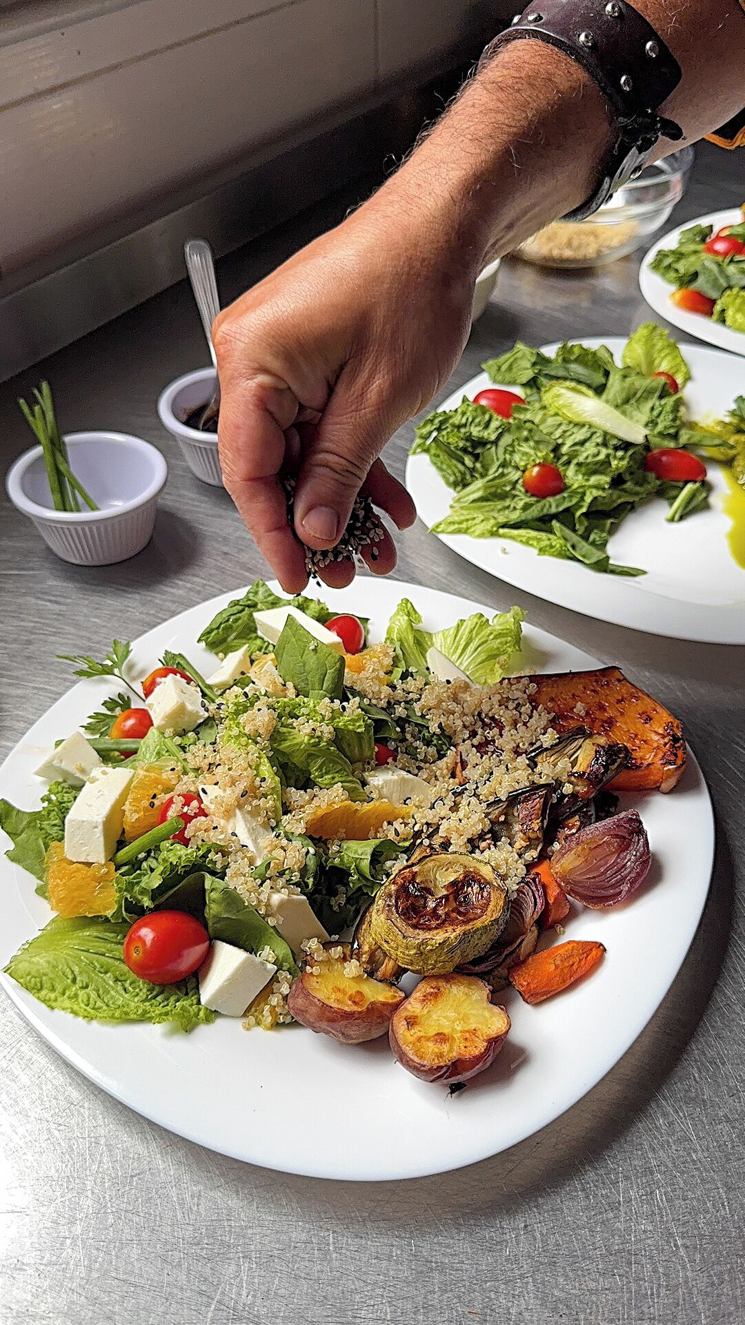 Una mano de chef esparciendo condimentos sobre un plato de comida.
