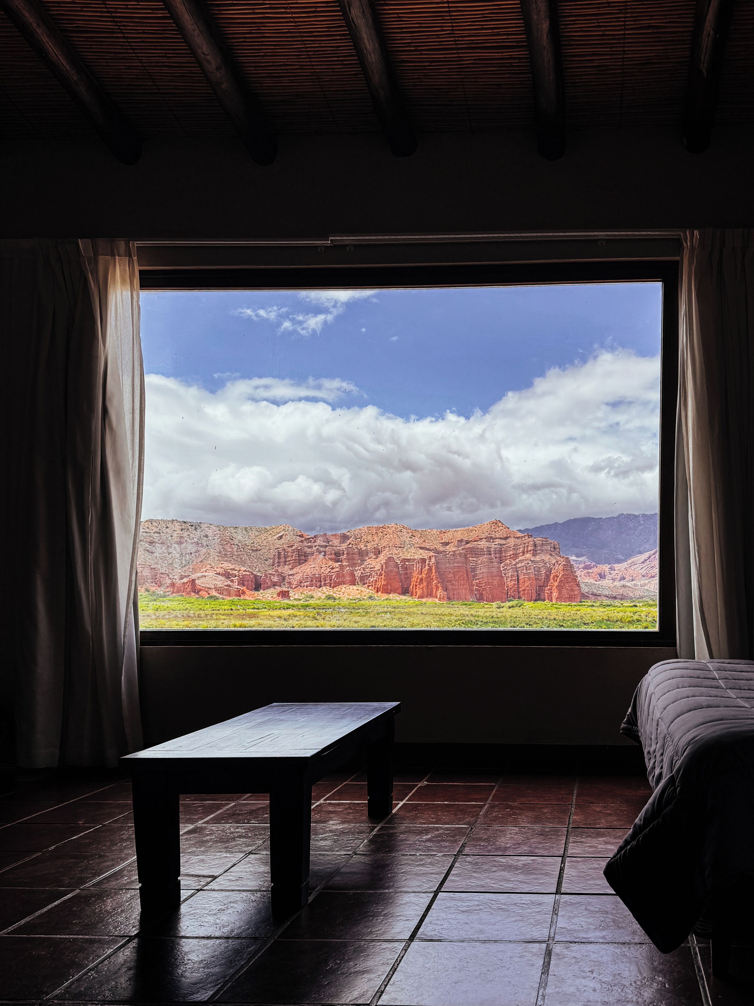 Una habitación con un ventanal grande, una cama y una mesa.