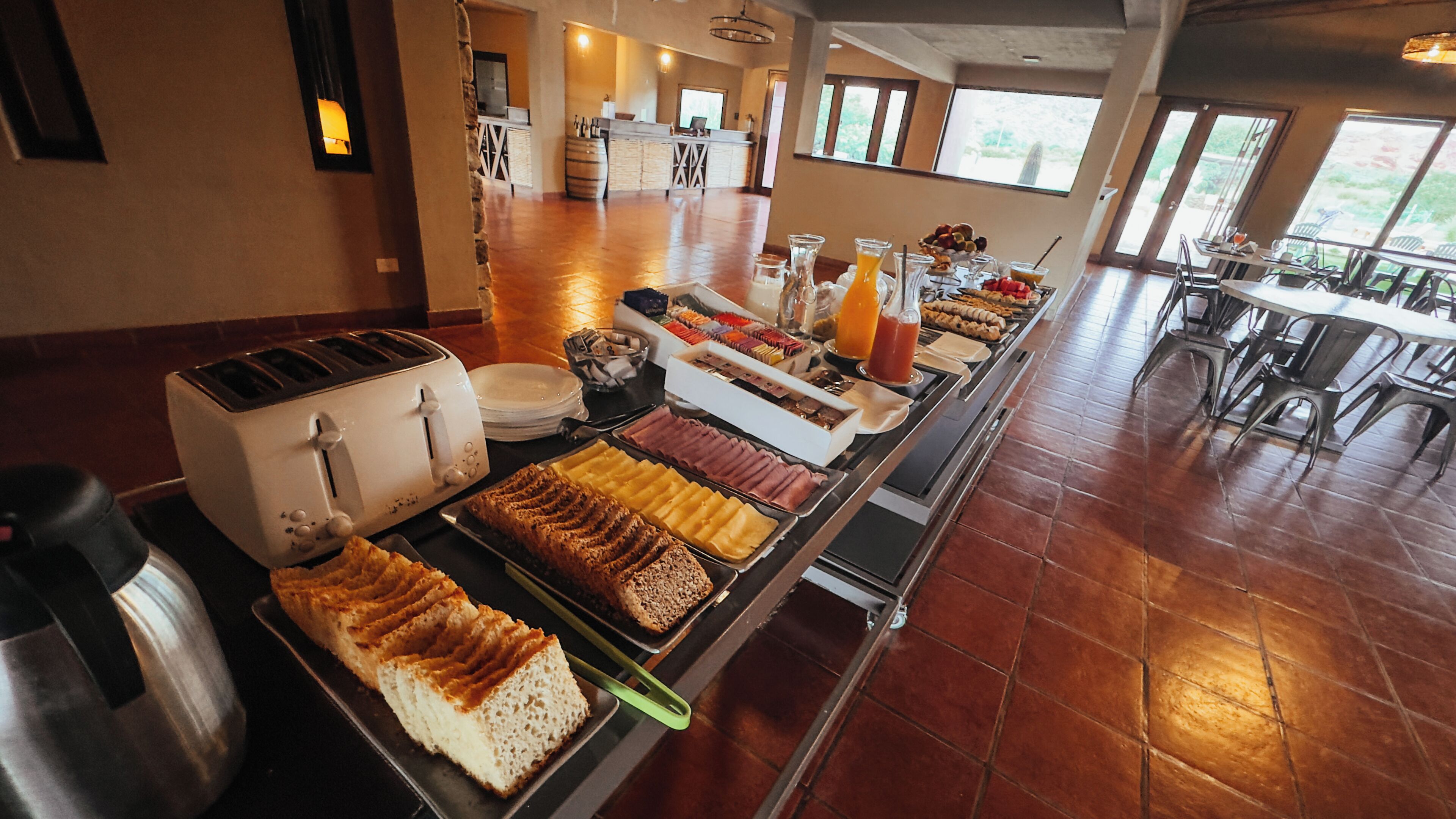 Un bufé con diversos alimentos, un tostador y una zona de cocina al fondo.