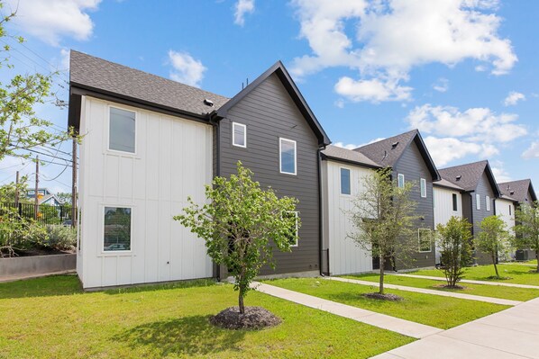 A row of modern houses with a well-maintained lawn and a clear sky.