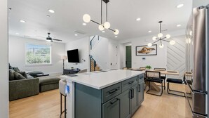 Een moderne keuken met een centraal eiland, inbouwapparatuur en een eethoek met tafel en stoelen.