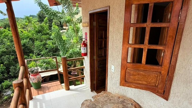 Ein Holztisch und -stühle auf einem Balkon mit Blick auf Grünflächen.