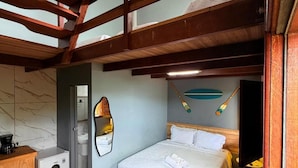 Ein Schlafzimmer mit einem Bett, einem kleinen Schreibtisch, einem Spiegel und einer Decke mit Holzbalken.