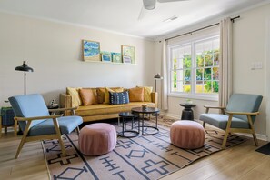 A living room with a sofa, two armchairs, a coffee table, and a rug. - Stay Here! | Next to Shem Creek | Minutes from CHS (Mount Pleasant)