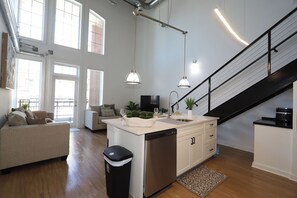 Eine moderne Küche mit Geschirrspüler, ein Essbereich mit einer Couch und eine Treppe.