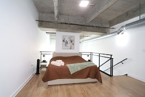 Ein Schlafzimmer mit Bett, einem Gemälde, einer Treppe und einer Heizung.