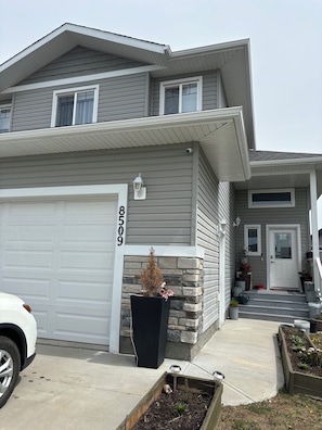 A two-story house with a garage, a stone accent wall, and a front door.