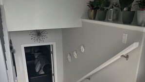 A staircase with a handrail, a door leading to a closet, and a shelf with potted plants. - Beautiful, quiet, clean, cozy and affordable house to host at least 10 guest. (Grande Prairie)