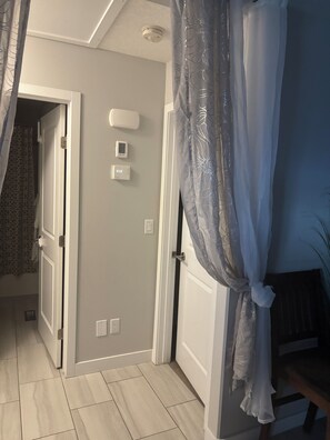 A hallway with a door, a thermostat, and a power outlet.