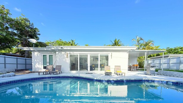 Ein modernes Haus mit Swimmingpool, überdachter Terrasse und eingezäunter Garten.