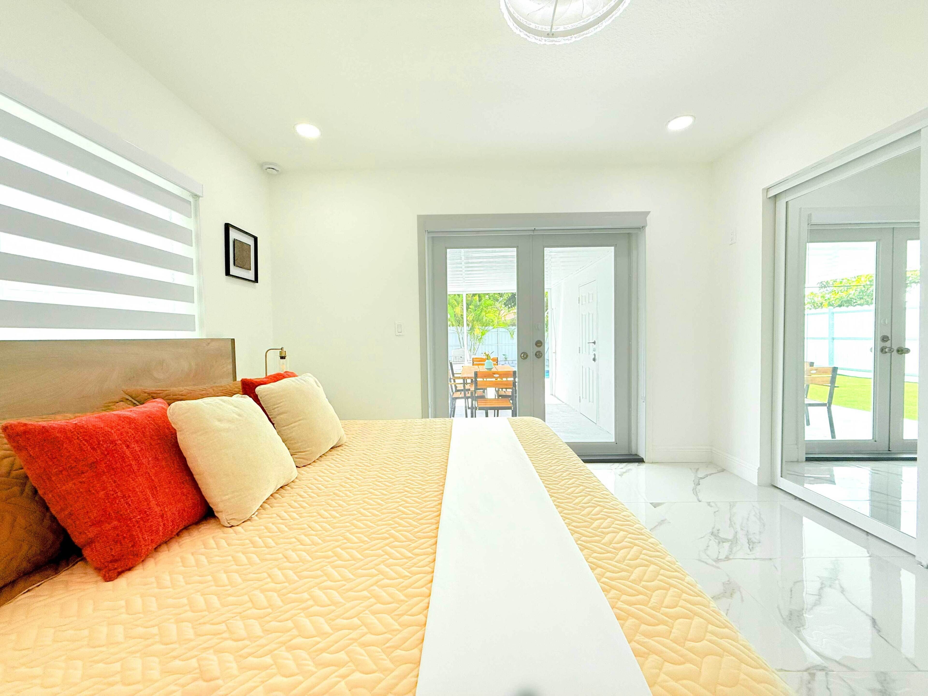 A modern hotel room with a large bed, a view of the outdoor patio, and a clean, minimalist design.