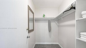 Une petite salle de bain fermée, équipée d’une douche, d’un miroir, d’un porte-serviettes et d’une étagère sur laquelle est posée une serviette.