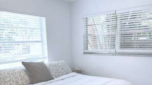 Une chambre à coucher avec un lit, un ventilateur de plafond et une fenêtre avec des stores.